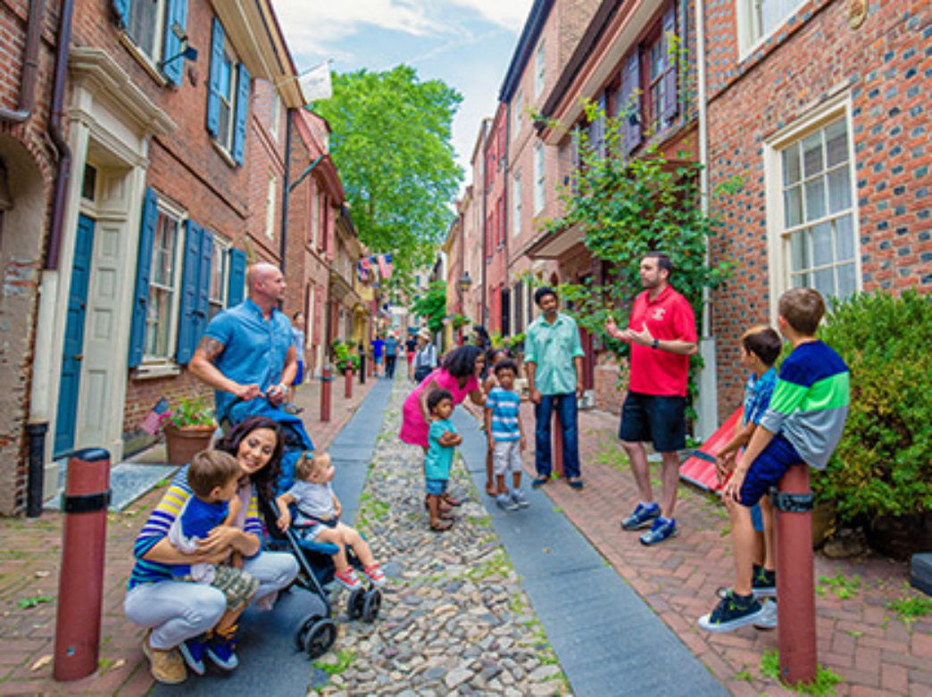 A tour guide in a red shirt educates tour goers in Elfreth's Alley in Philadelphia