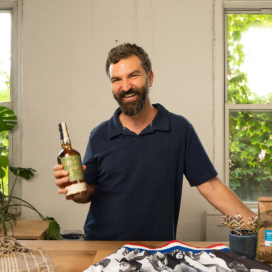 Director Jeremiah Zagar smiles at the camera while holding whiskey