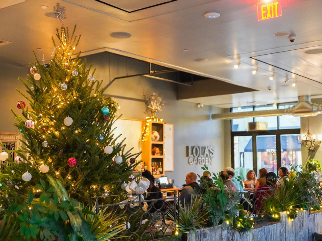 People sit at tables inside Lola's Garden, which is decorated for Christmas