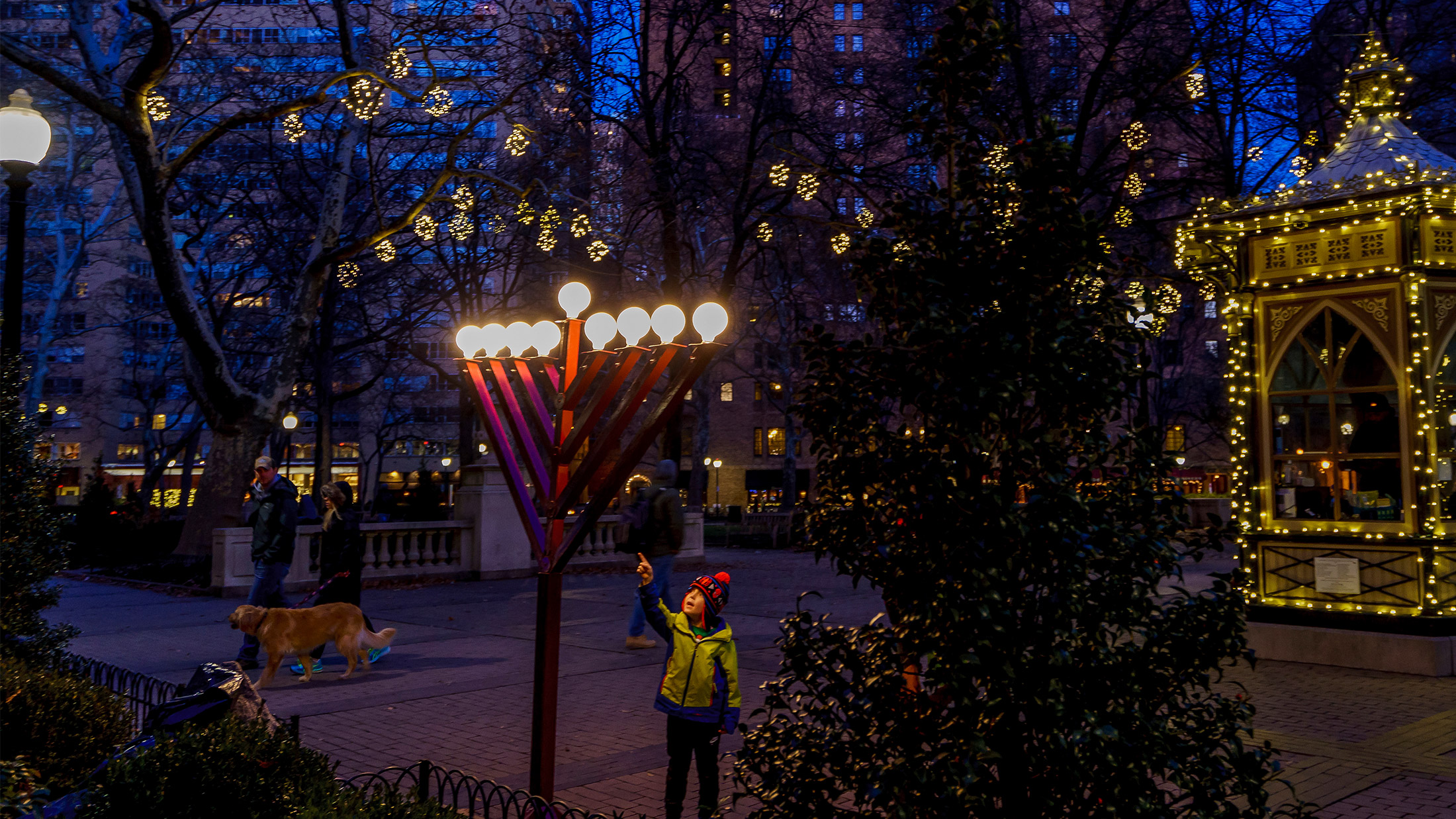 A young child points to a lit menorah in Rittenhouse Square