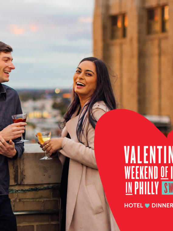 Two people holding drinks laugh while standing on a roofdeck. Text describes a Valentine's Day Sweepstakes in the bottom-right corner