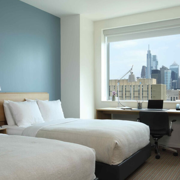 A hotel room with two beds. The Philadelphia skyline is outside the window.