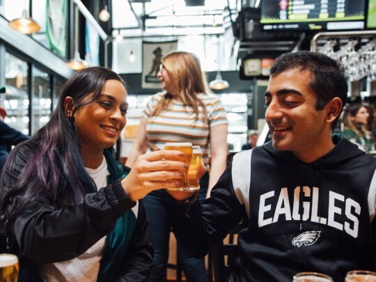 Two people toast with tiny beers at Yards Brewing Company in Philadelphia