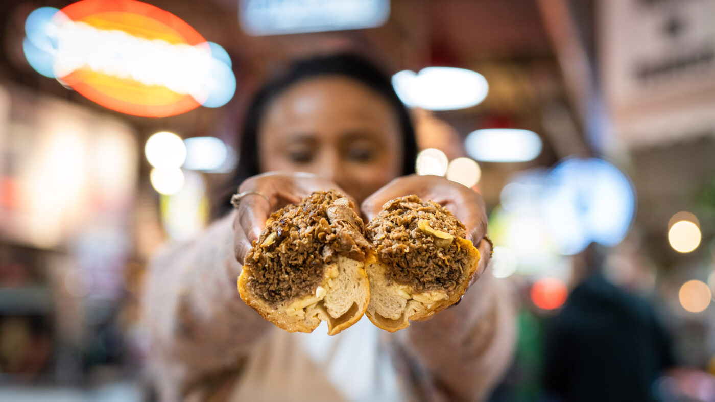 Femme tenant un cheesesteak à Reading Terminal Market