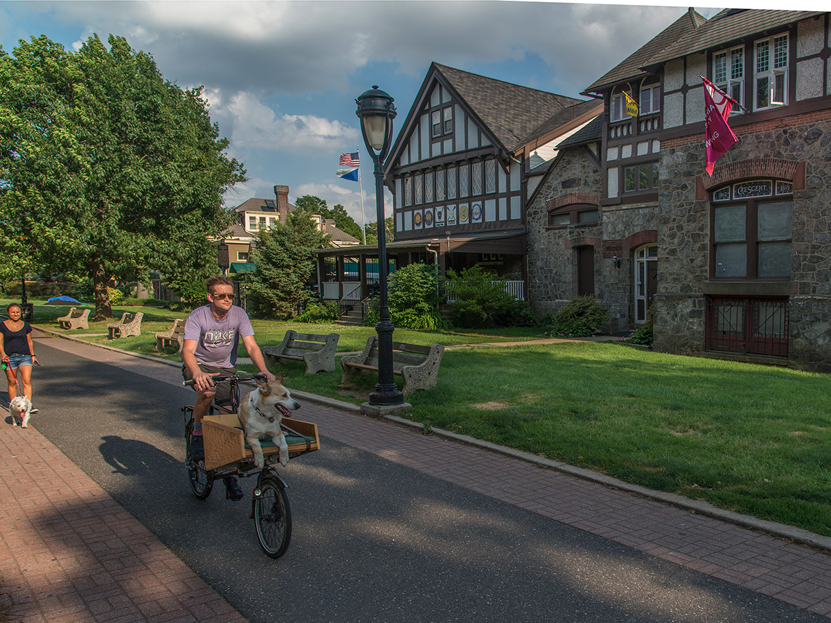 People bike and walk past a house on Boathouse Row in Philadelphia on the Schuylkill River Trail