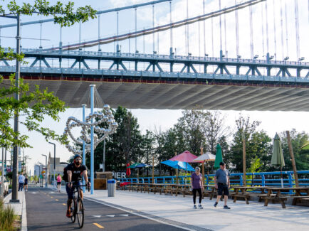 Man biking and couple walking along the Delaware River Trail