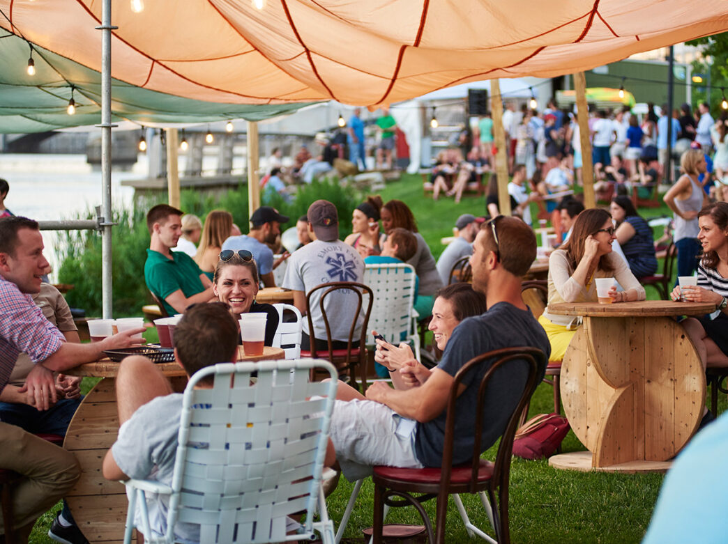 People sit around picnic tables at a beer garden.
