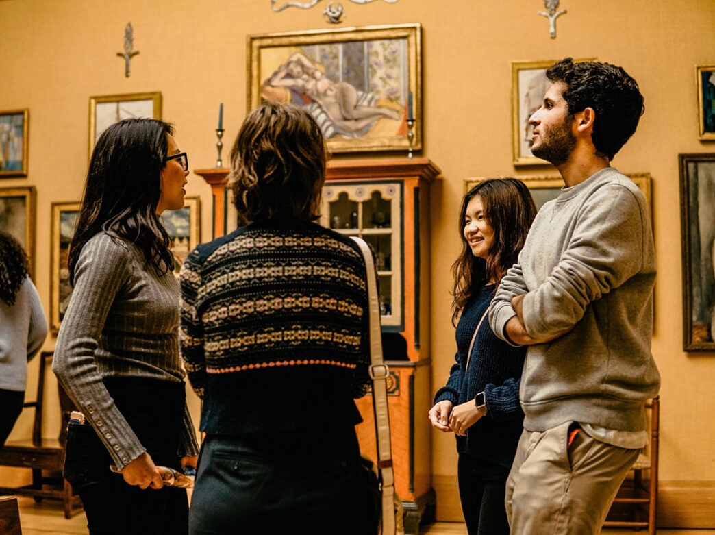 A group of college students chat with one another in a semi-circle at the Barnes Foundation.