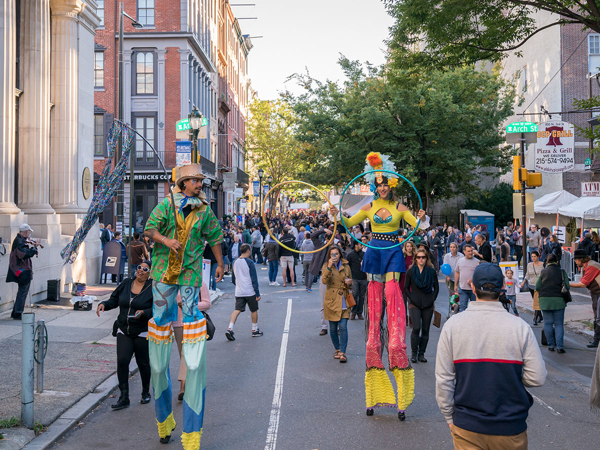 Two circus performers on stilts walk through a crowd at Old City Fest.