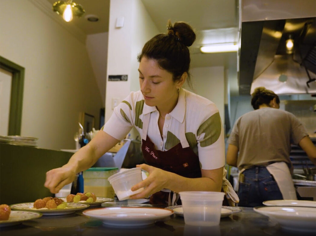 Chef Amanda Shulman leans over a plate of food at Her Place Supper Club in Philadelphia