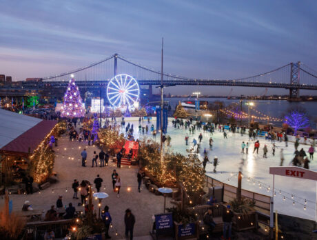 A wideshot of Independence Blue Cross RiverRink Winterfest at dusk. The Benjamin Franklin Bridge is visible in the background.