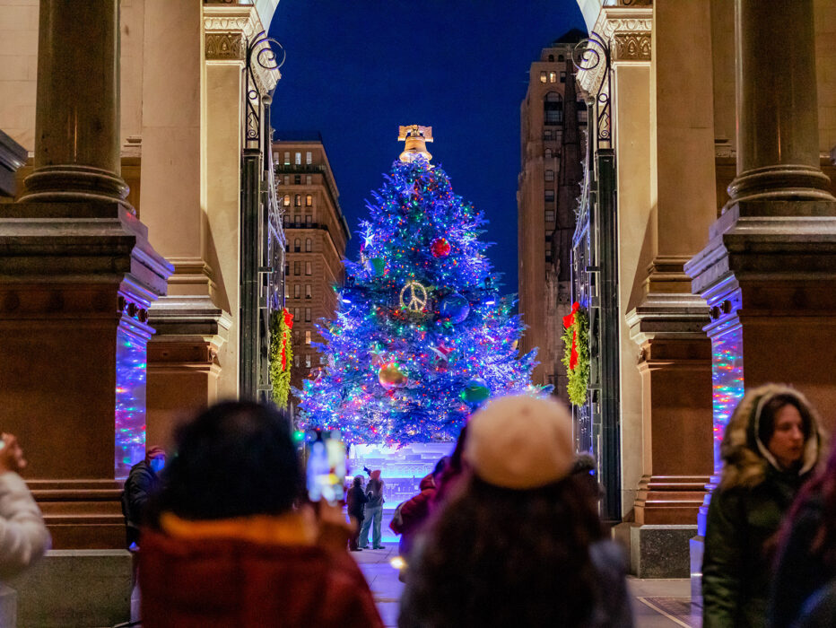 Children stand in the foreground while the VIsit Philadelphia Holiday Tree glows in the background