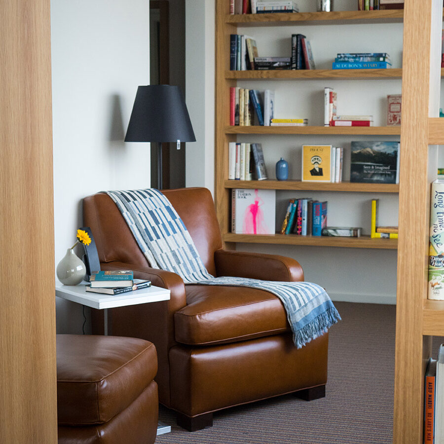 A comfy chair with books on shelves in the background at The Study in Philadelphia