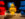Three large sculptures - one red, one yellow, and one blue - of people made of LEGO® bricks are illuminated in a dark exhibit gallery.