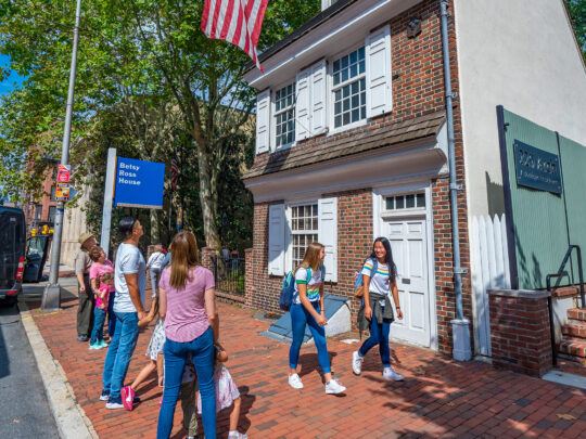 Family viewing and teenagers walking by the exterior of the Betsy Ross House.