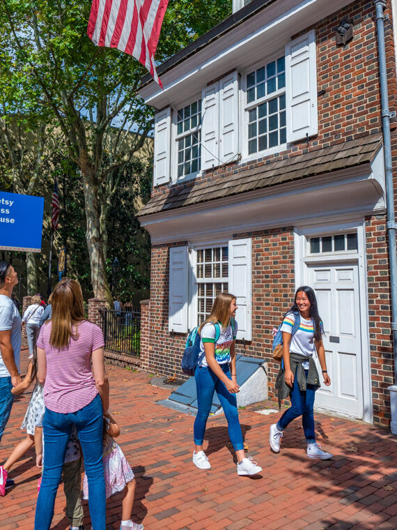 Family viewing and teenagers walking by the exterior of the Betsy Ross House.