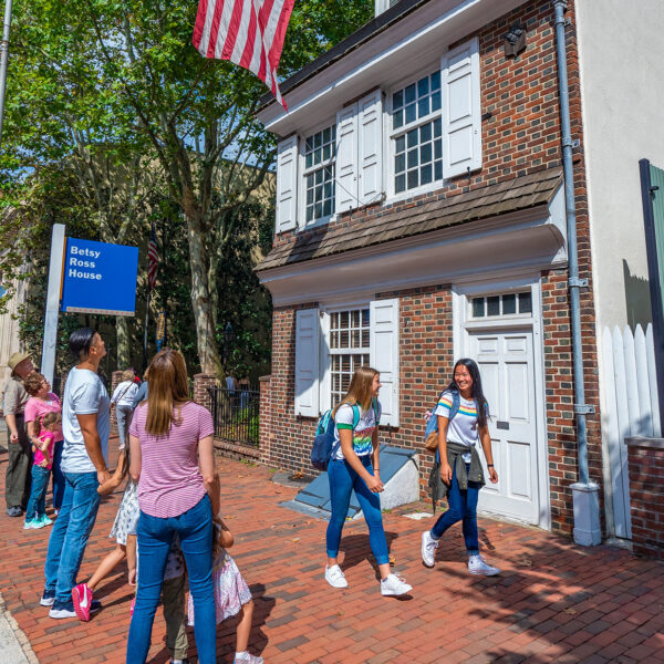 Family viewing and teenagers walking by the exterior of the Betsy Ross House.