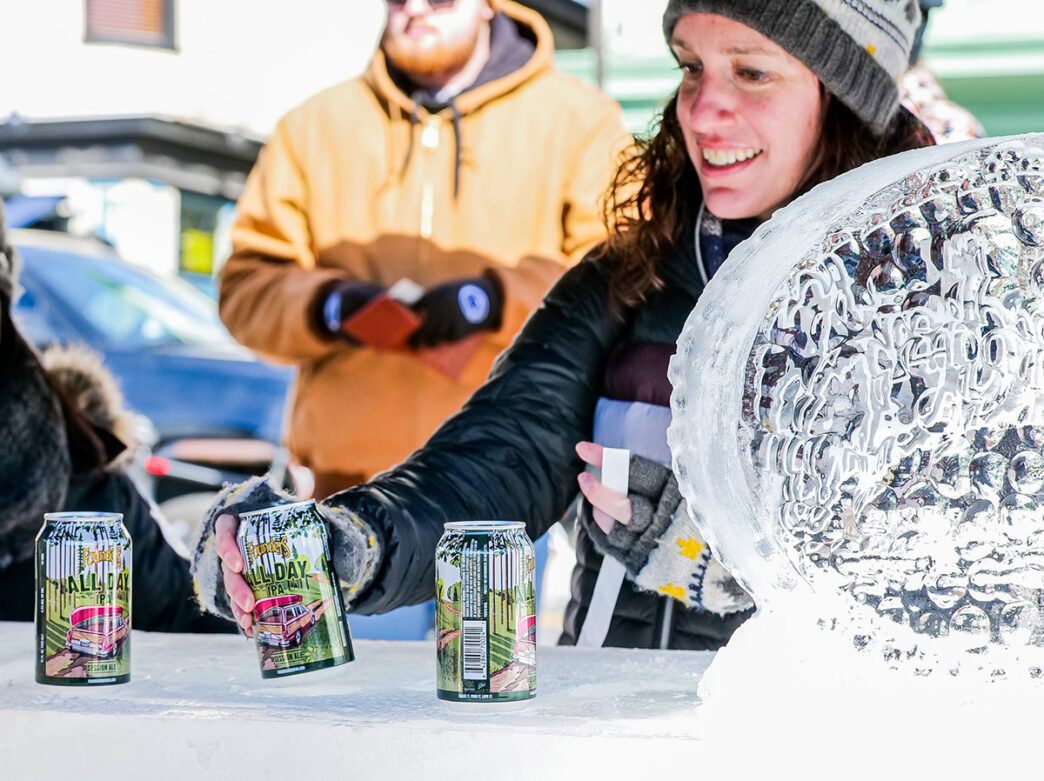Person grabs for Founders Brewing beer can with oval ice sculpture on right side of image.