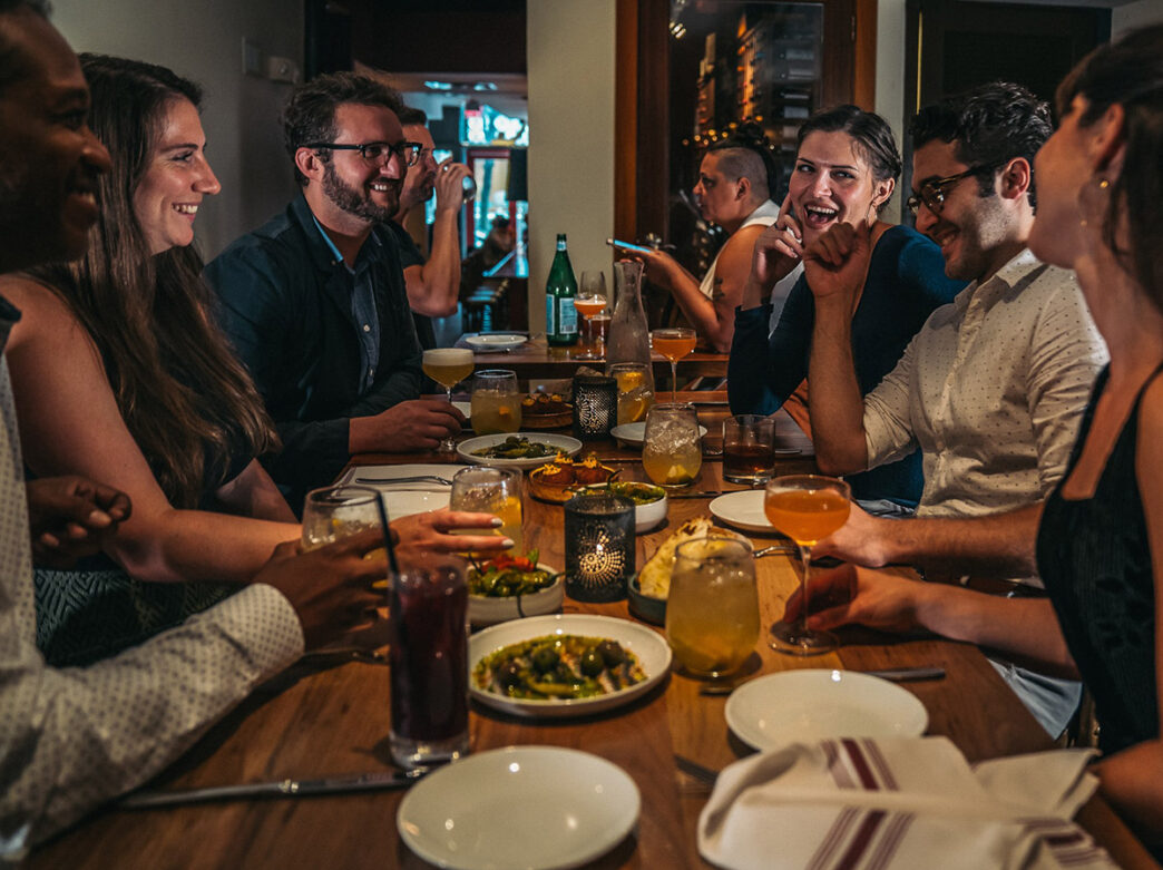 A group of people sit around a dining table with plates of food at Oloroso in Philadelphia.