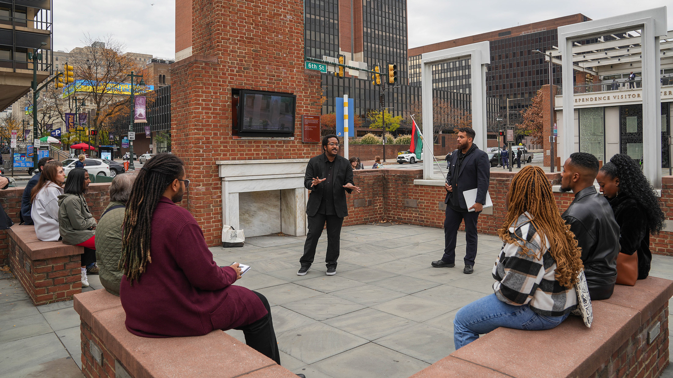 A tour guide from The Black Journey speaks to a group of seated tourgoers at The President's House in Philadelphia