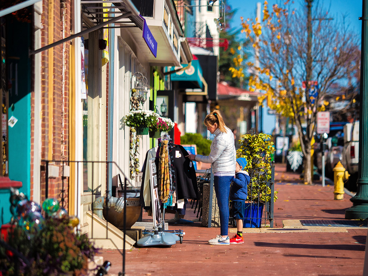 Des femmes et un enfant examinent un présentoir de vêtements à l'extérieur d'un magasin dans le quartier commerçant de West Chester.