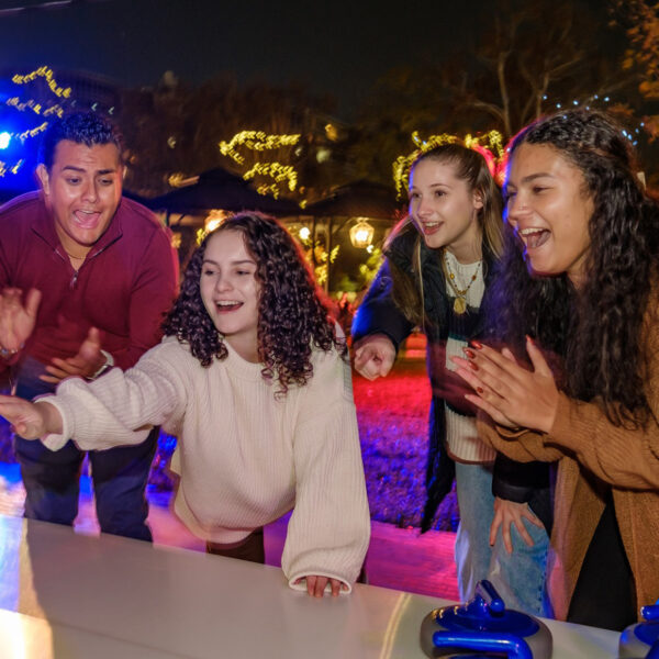 A young girl plays a game of street curling while three people clap and cheer.