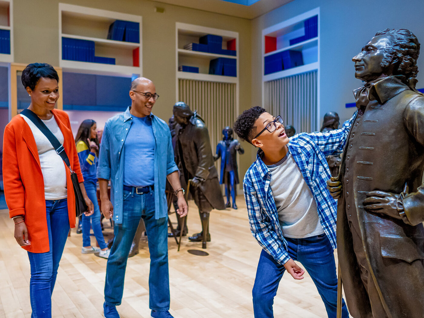 Family excitedly looking at statues of founding fathers at the National Constitution Center