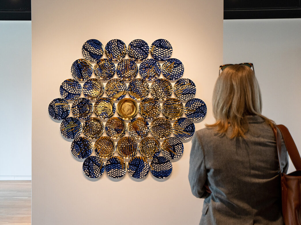 A person looks at a piece of clay artwork displayed in a hexagon shape in a gallery at The Clay Studio in Philadelphia.