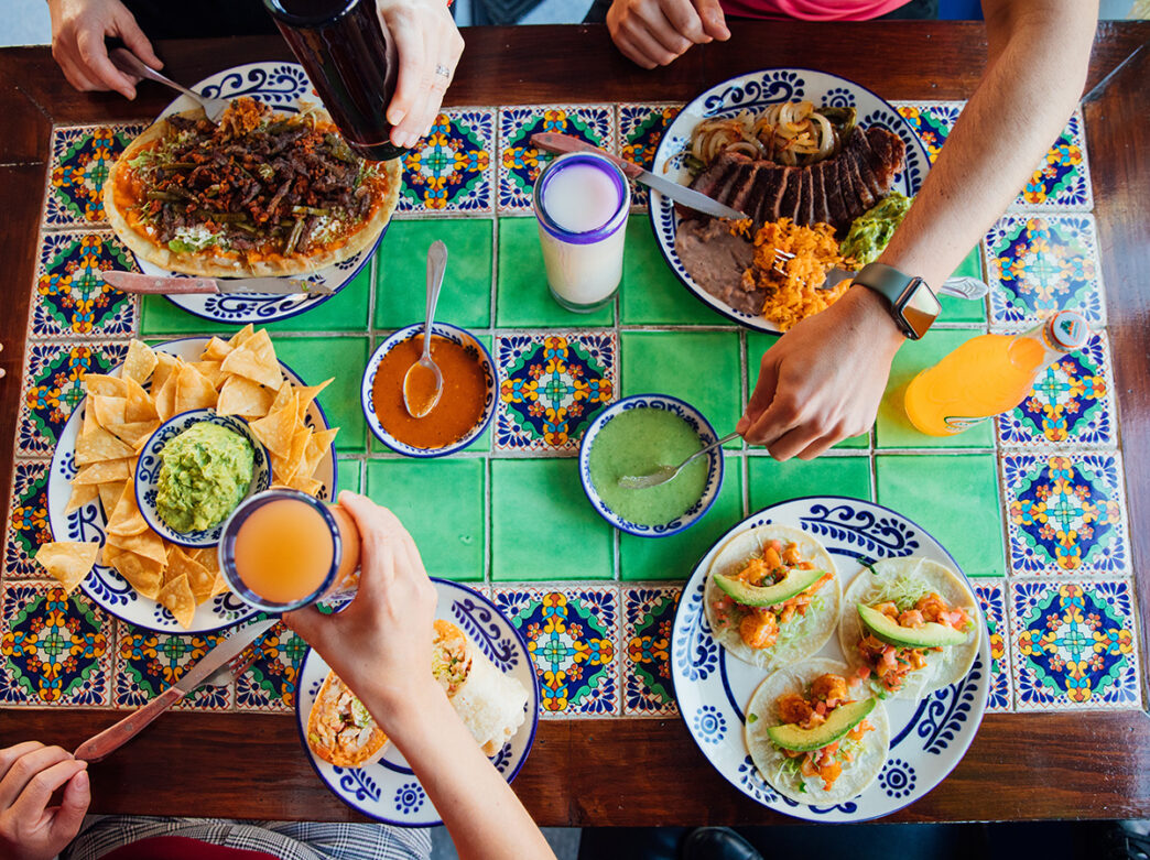 Tacos, huarache, carne asada, chips and salsa are displayed on a ceramic tile table at Los Cuatro Soles in Philadelphia.