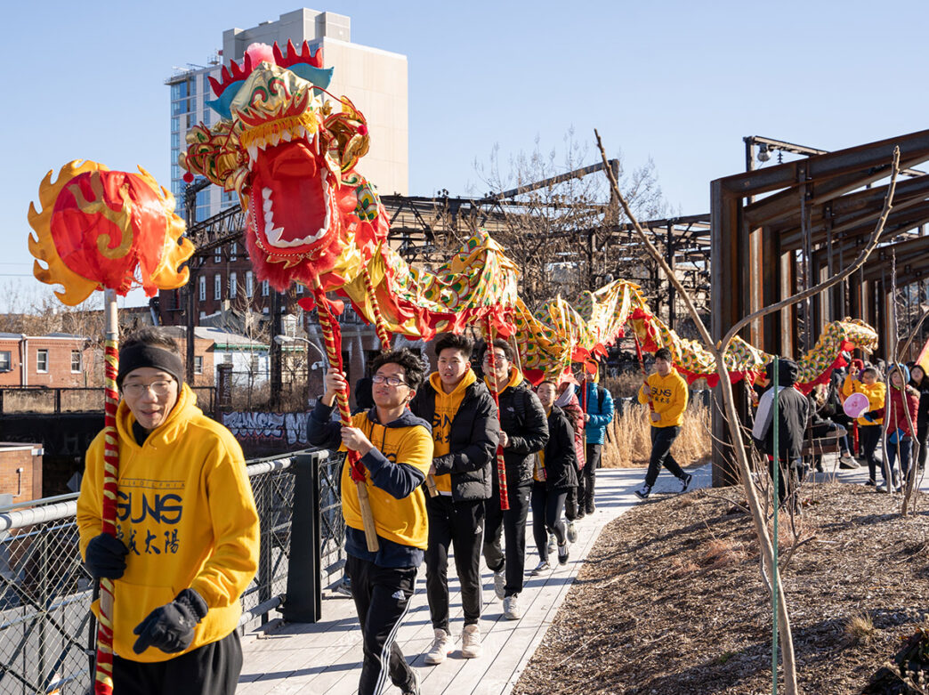 Philadelphia Suns group carrying giant yellow and red dragon puppet through the Rail Park in Philadelphia.