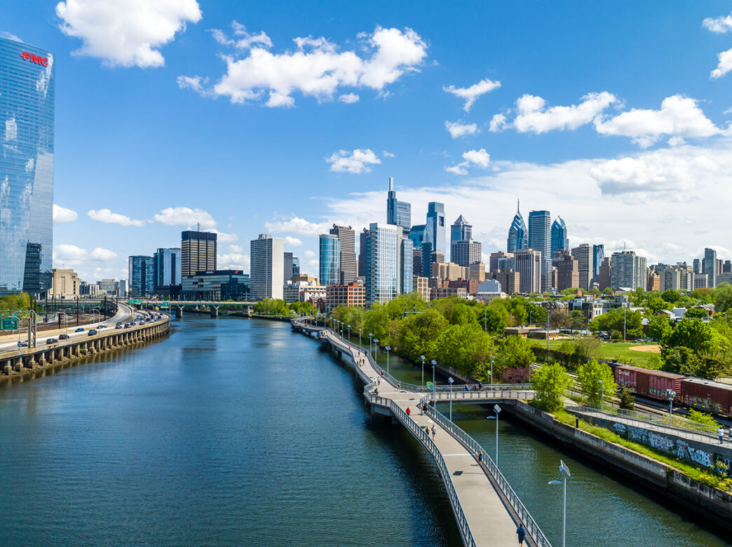 L'horizon de Philadelphie par une journée ensoleillée, avec la rivière Schuylkill et la promenade Schuylkill Banks au premier plan.
