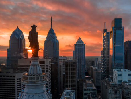 Het standbeeld van William Penn bovenop City Hall en de skyline van Philadelphia bij zonsondergang.
