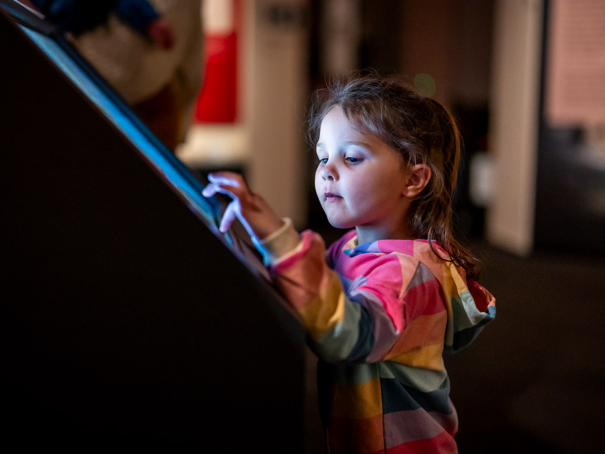 A young guest using one of the interactive screens within the Witness to Revolution exhibit.