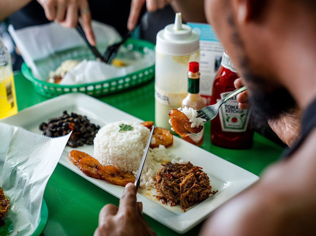 The camera looks over the shoulder of a person eating a meal at Arepa Grub Spot in Philadelphia.