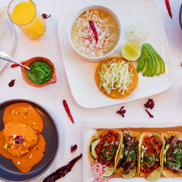 Tacos, pozole, Aztec soup, sauces and side dishes are displayed on a table with a white tablecloth at Casa Mexico in Philadelphia.