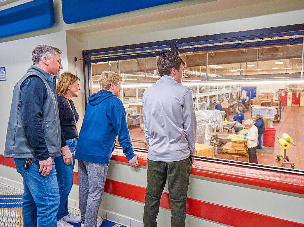 A family on a factory tour looks through a window into the Herr's Factory.
