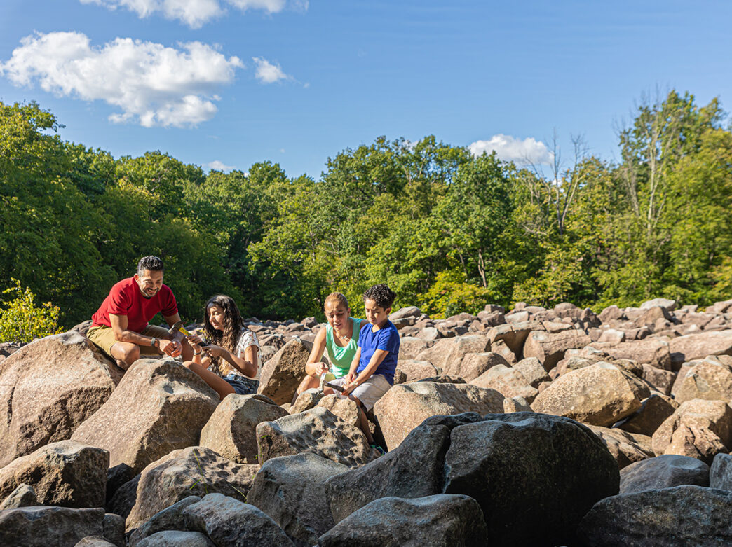 A family of four uses hammers to strike the boulders at Ringing Rocks Park in Bucks County, PA.