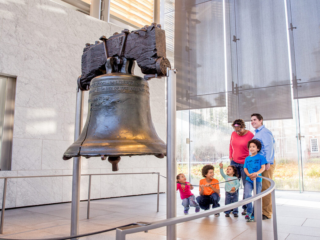 Um casal e quatro crianças olham e admiram o Liberty Bell.