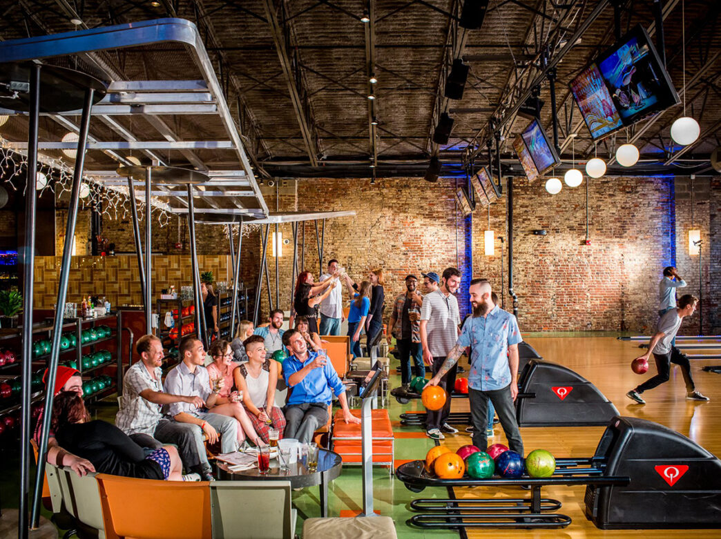 Gente jugando a los bolos y sentada detrás de las pistas con bebidas en North Bowl en Filadelfia.