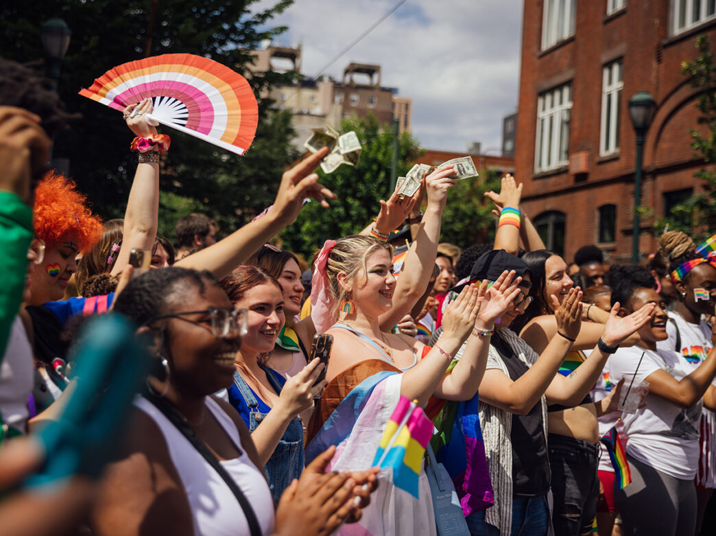 Des personnes portant des tenues et des accessoires arc-en-ciel applaudissent et applaudissent pendant la Marche des Fiertés et le Festival de Philadelphie.