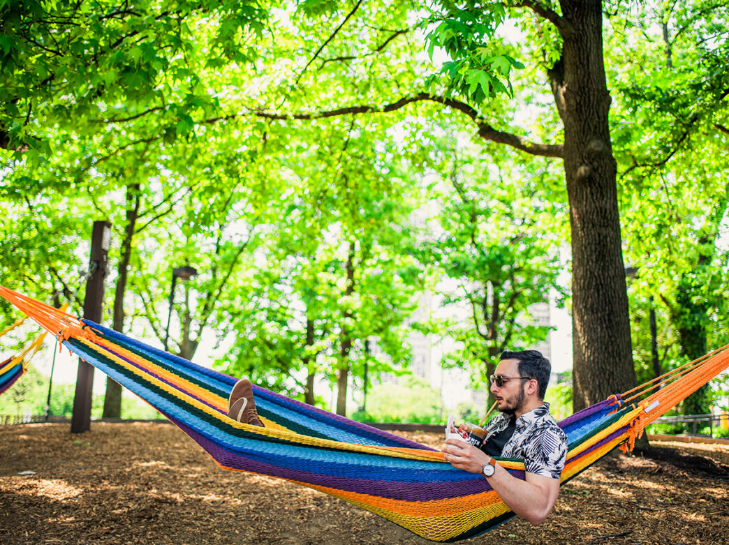 Une personne s'allonge dans un hamac tout en buvant une boisson avec une paille au Spruce Street Harbor Park à Philadelphie.