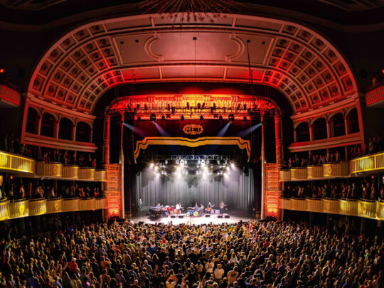 A band performs on stage at The Met in Philadelphia while the crowd faces the stage.