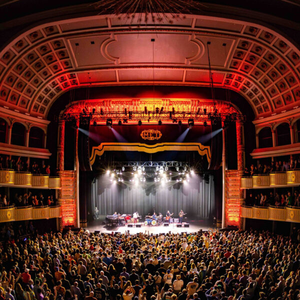 A band performs on stage at The Met in Philadelphia while the crowd faces the stage.