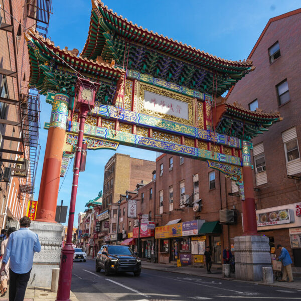 People walking on the sidewalk through Chinatown near the Friendship Gate