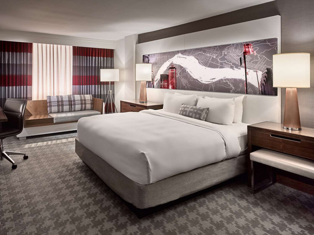 King guest room at Sonesta Philadelphia Rittenhouse Square. The room has gray carpeting with red and gray curtains.