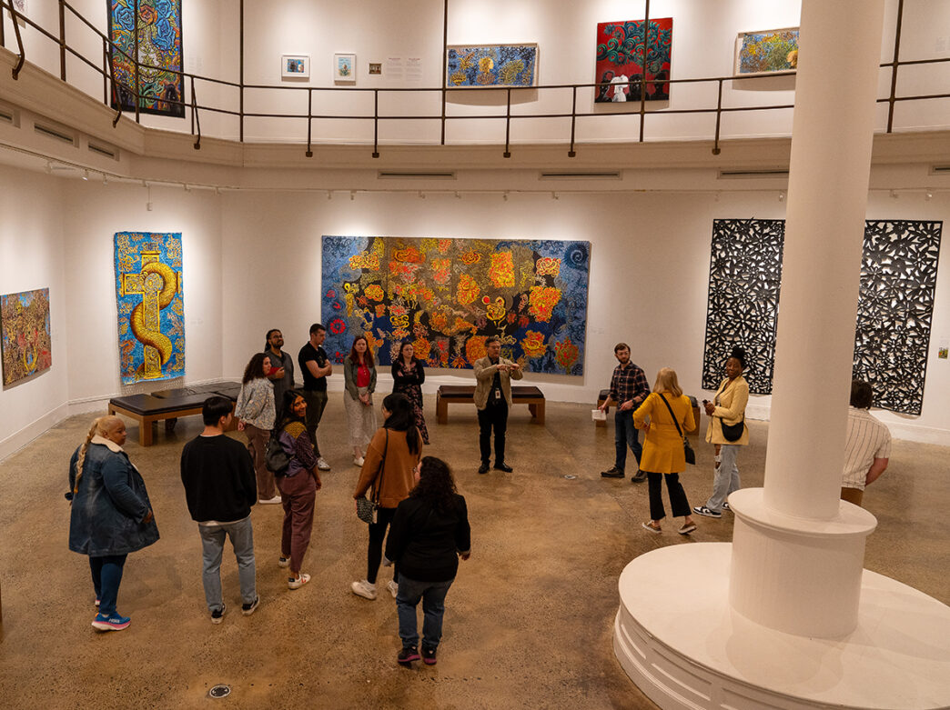 Visitors walk around a gallery displaying colorful artwork by Henry Bermudez at the Woodmere Art Museum.