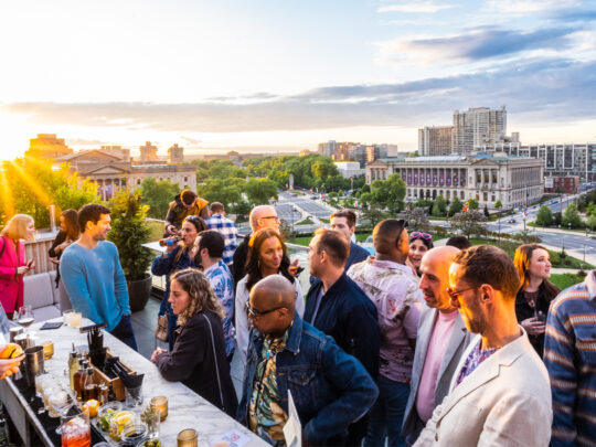 Les clients commandent des boissons à l'Assembly Rooftop Lounge avec vue sur la bibliothèque centrale Parkway en arrière-plan, alors que le soleil se couche.