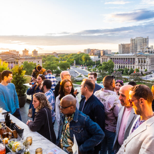 La gente pide bebidas en el Assembly Rooftop Lounge con vistas a la Biblioteca Central Parkway al fondo mientras se pone el sol.