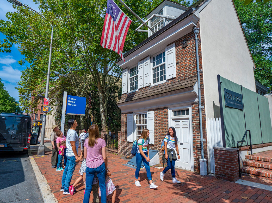 Family viewing and teenagers walking by the exterior of the Betsy Ross House.