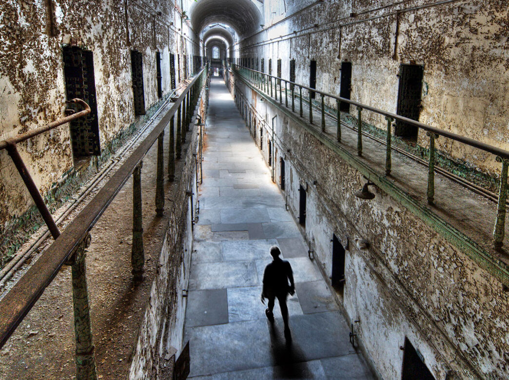 Un visiteur se promène dans les couloirs de Eastern State Penitentiary.